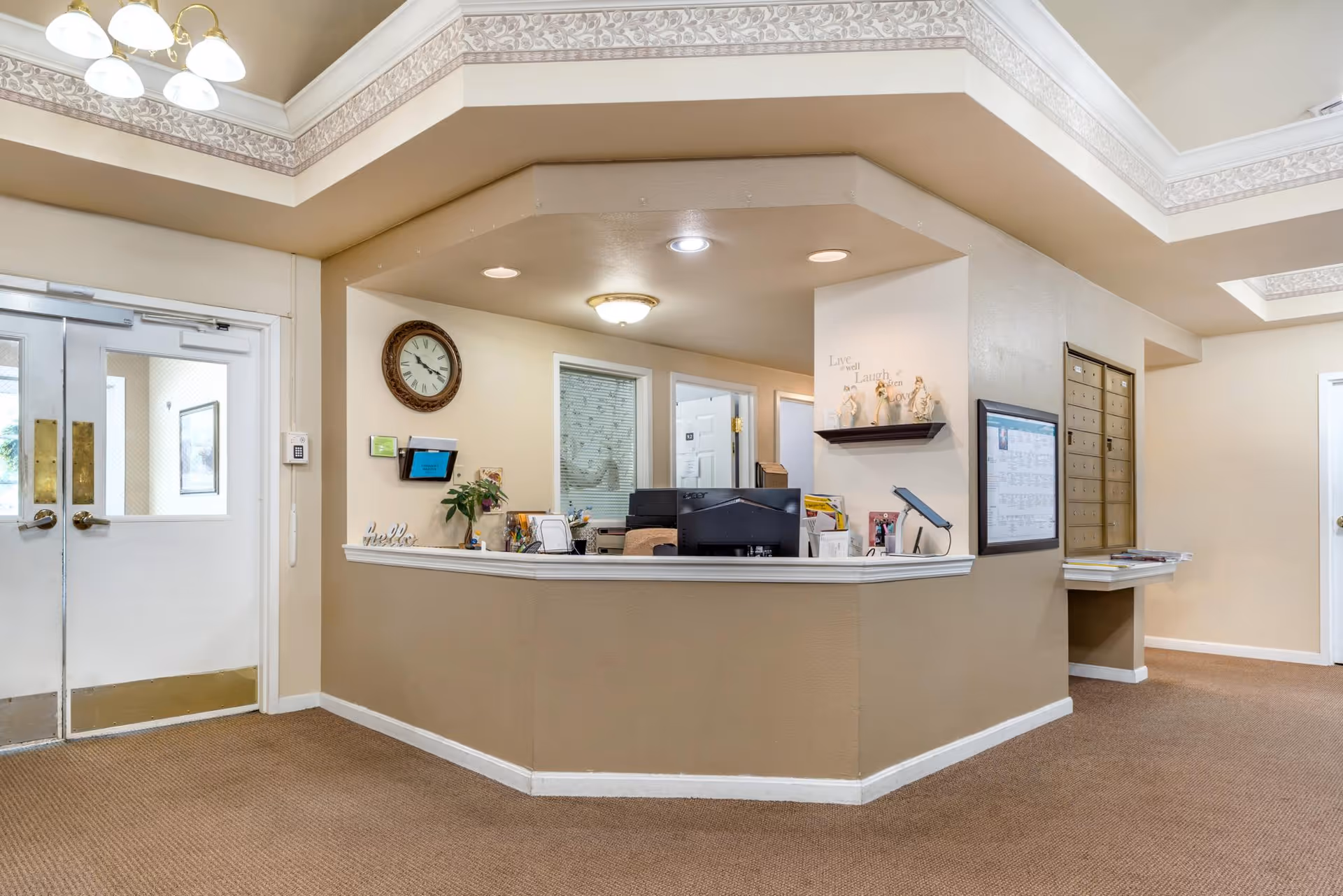 Front desk reception area with a service counter, mailboxes, and double glass doors in a lobby.