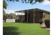 Front exterior of the Pioneer Health Care Center building with a covered entrance, sign, and well-kept lawn.