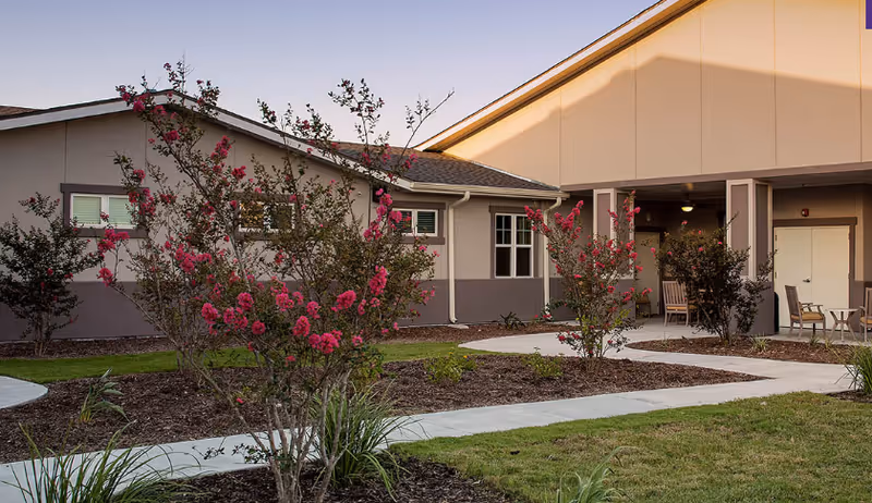 Exterior view of St. Gabriel of Corpus Christi Memory Care with landscaped path and seating.