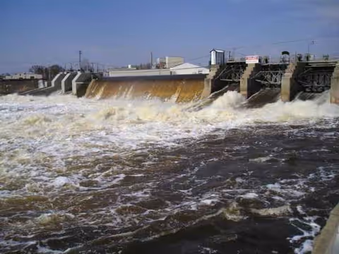 Rushing water spills over a dam-like structure with industrial gates outdoors