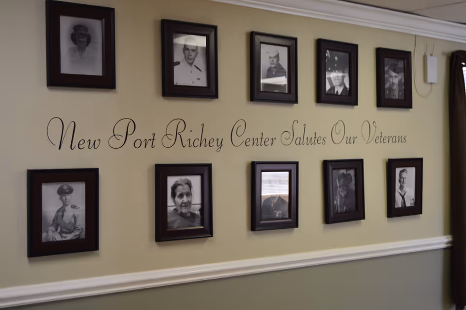 Interior wall display of framed black-and-white portraits with the script text 'New Port Richey Center Salutes Our Veterans'.