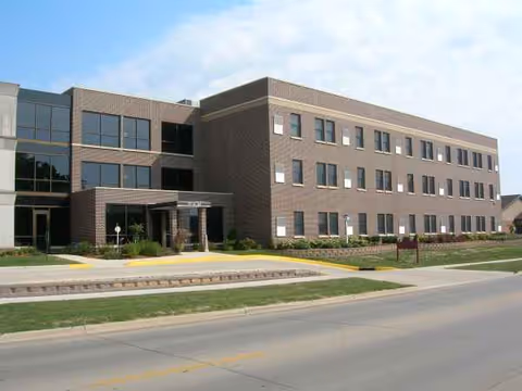 Brick, multi-story senior living facility exterior with glass entrance and landscaped front area.