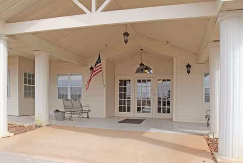 Front entrance of Hoyt Court senior living facility with white columns and American flag.