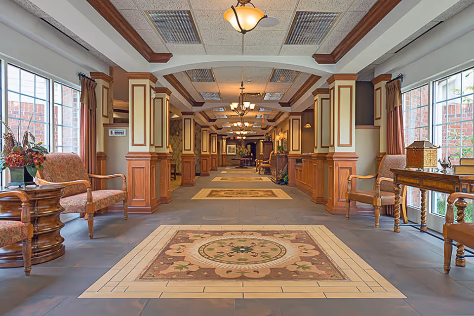 Spacious decorated lobby hallway with seating, columns, chandeliers and patterned floor tiles.
