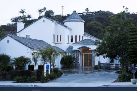 Bel Age senior living facility exterior with white walls, curved towers, and a wooden entrance.