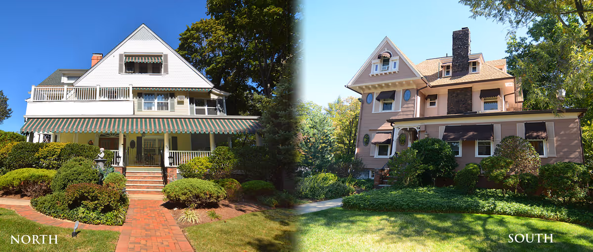 Side-by-side exterior views of two large, multi-story houses surrounded by greenery and landscaping. The left house has a white facade with a striped awning and a brick pathway leading to the entrance, labeled 'NORTH'. The right house has a beige facade with multiple windows and a chimney, labeled 'SOUTH'. Both houses are set against a backdrop of trees under a clear blue sky.
