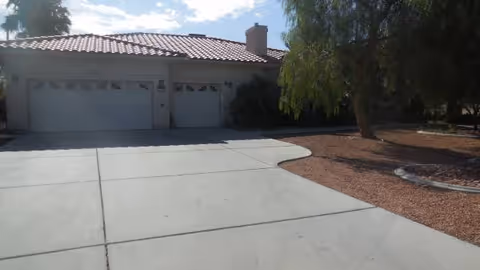 Front exterior of a single-story home with a concrete driveway and landscaped yard.