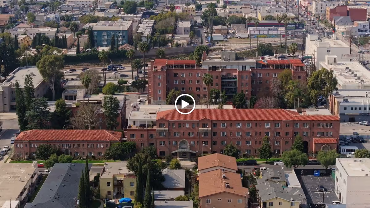 Aerial view of Kingsley Manor, a large multi-story residential building with red-tiled roofs surrounded by trees and other buildings in an urban area.