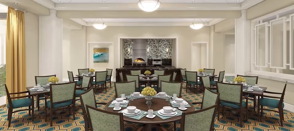 Dining room with round tables set with dishes, green-upholstered chairs, patterned carpet, and a service area at the back.