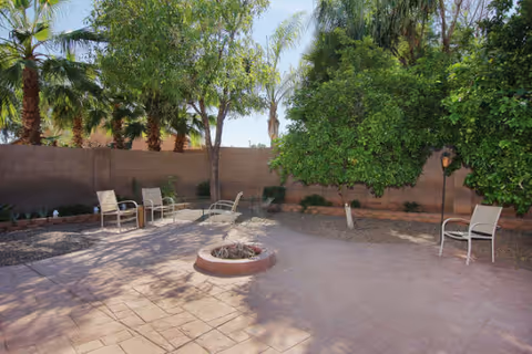 Outdoor patio with metal chairs, trees, and a circular central fire pit.
