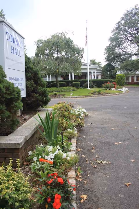 Exterior view of Cornell Hall Care & Rehabilitation Center with landscaped entrance and sign.
