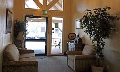 Cozy seating area in a senior living lobby with sofas, chairs, and plants.