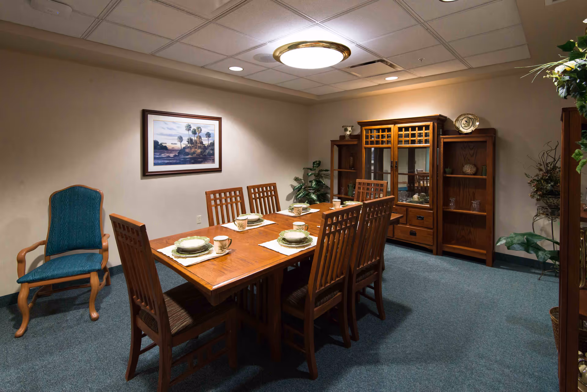 A wooden dining table set for eight in a formal room with a china cabinet.