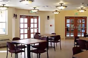 Interior dining room with several tables, chairs, and glass doors.