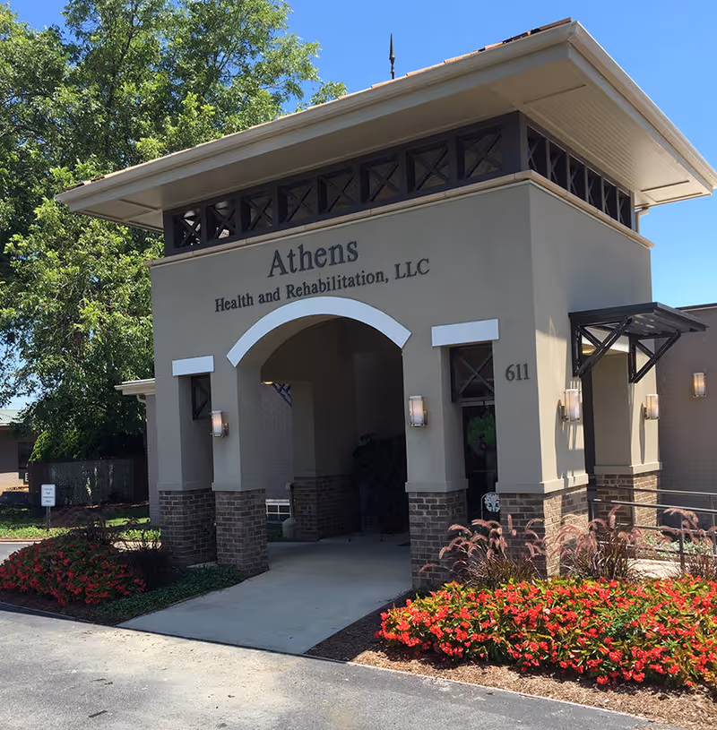 Front entrance of Athens Health and Rehabilitation, LLC with an arched portico, address number 611, and flowerbeds.