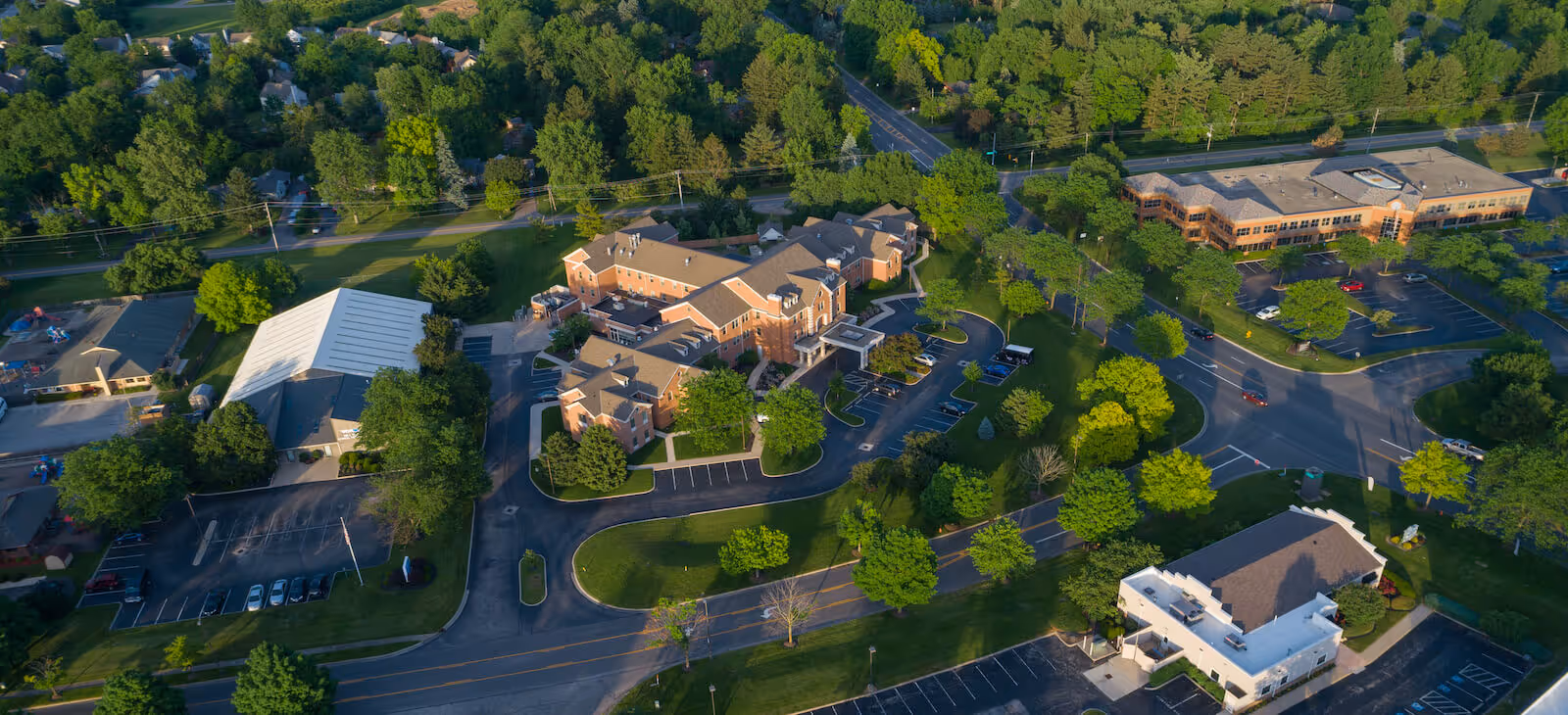 Aerial view of the Harmony Trace campus showing multiple connected brick buildings, parking areas and surrounding trees and roads.