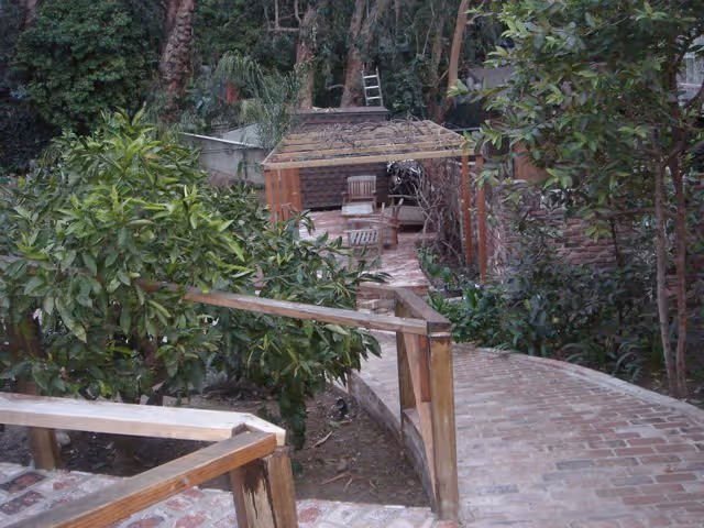 Outdoor brick walkway through a Brentwood on Sunset garden leads to a shaded seating area.