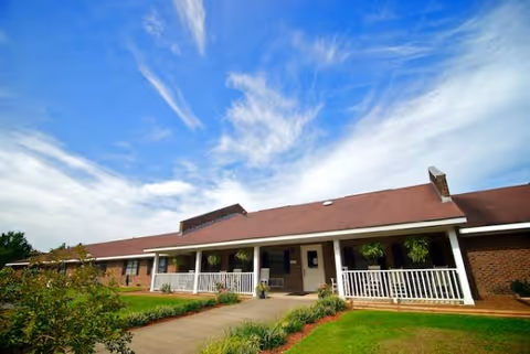 Single-story assisted living building with a front porch and well-kept landscaping.