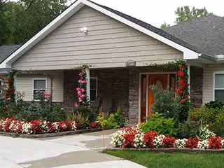 Front exterior of Orchard Manor senior living building with colorful flower beds.