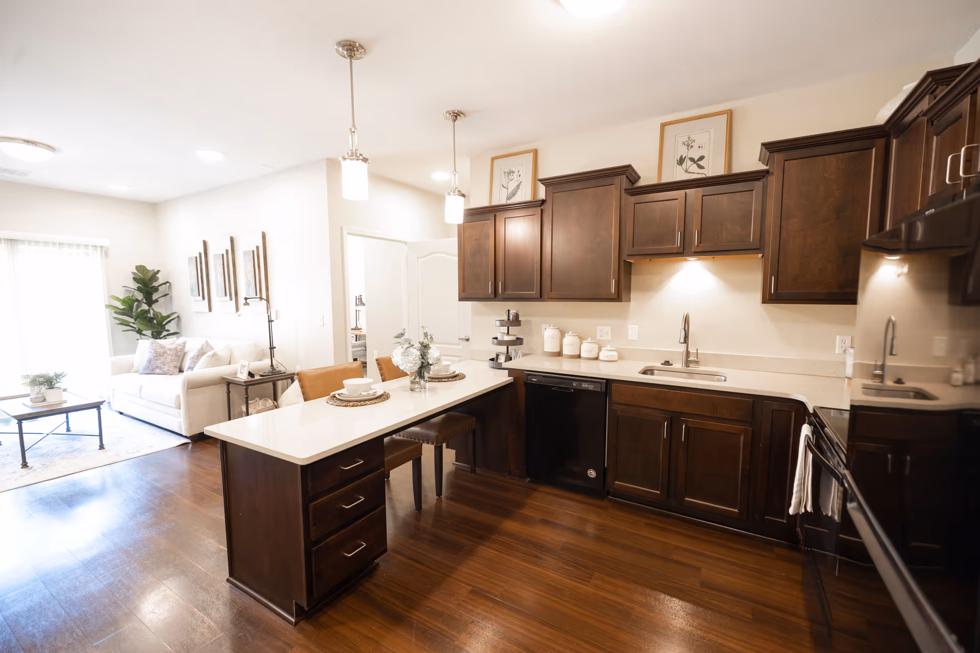 Open-concept kitchen featuring dark wood cabinets, a white island with seating and a connected living area.