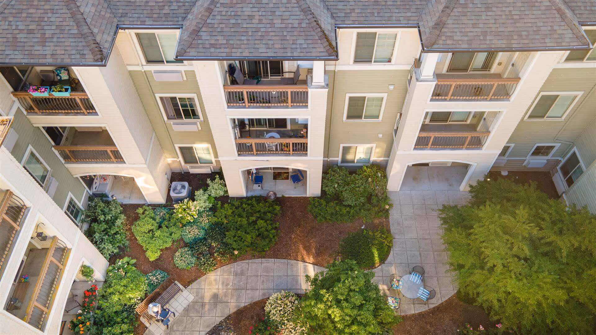 Aerial view of a landscaped courtyard with walkways, seating, and surrounding apartment balconies.