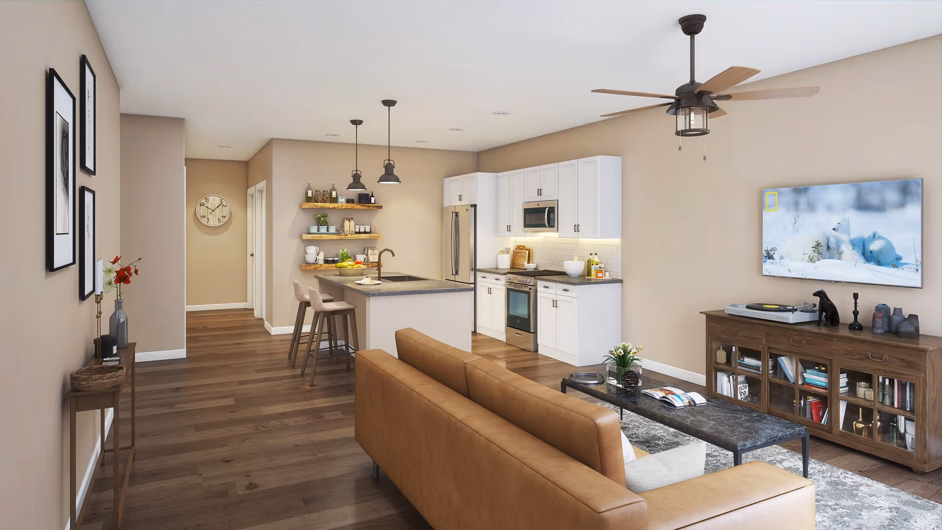 Open-plan living area with a brown leather sofa facing a wall-mounted TV and a kitchen island with bar stools in the background.