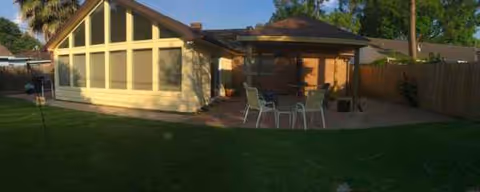 Exterior of a single-story assisted living home with a shaded patio and outdoor seating.