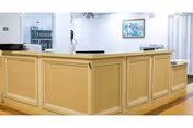 Light-wood reception desk in a clean, bright interior space.