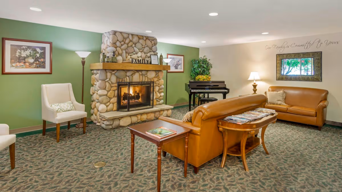 Cozy common room with a stone fireplace, leather sofas, armchairs, a piano and side tables.