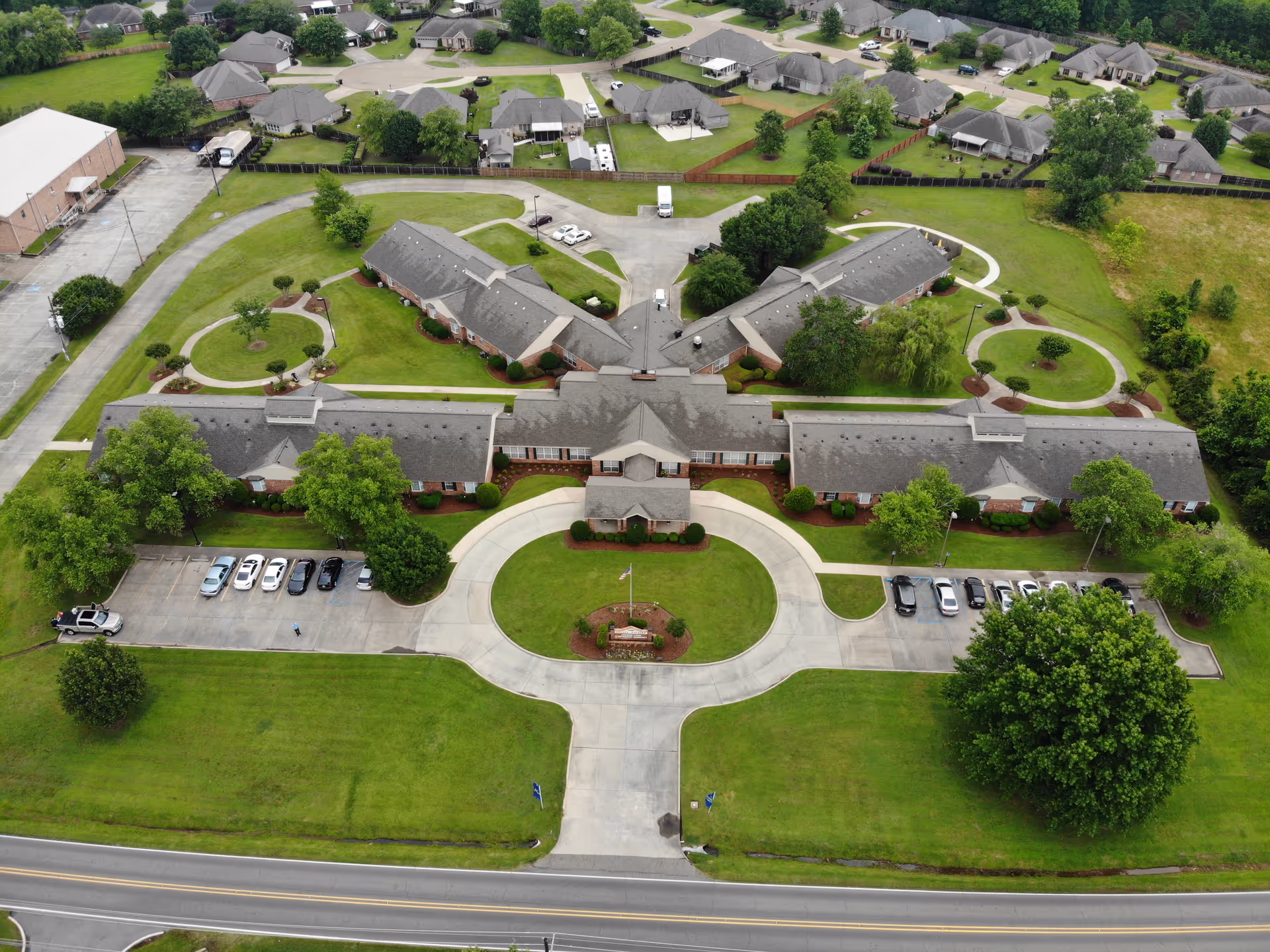Aerial view of Azalea Estates of Monroe senior living complex with a circular driveway, parking lots, and landscaped lawns.