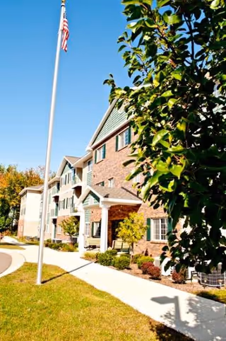 Exterior view of Maxwell Place senior living building with a flagpole and landscaped entrance.