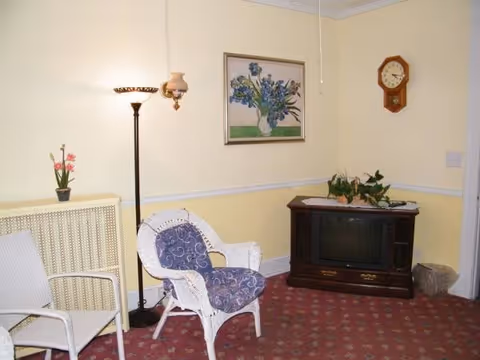 A cozy living room with wicker chairs, a TV cabinet, and plants.