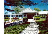 Front view of a senior care facility with a stone walkway and landscaping.