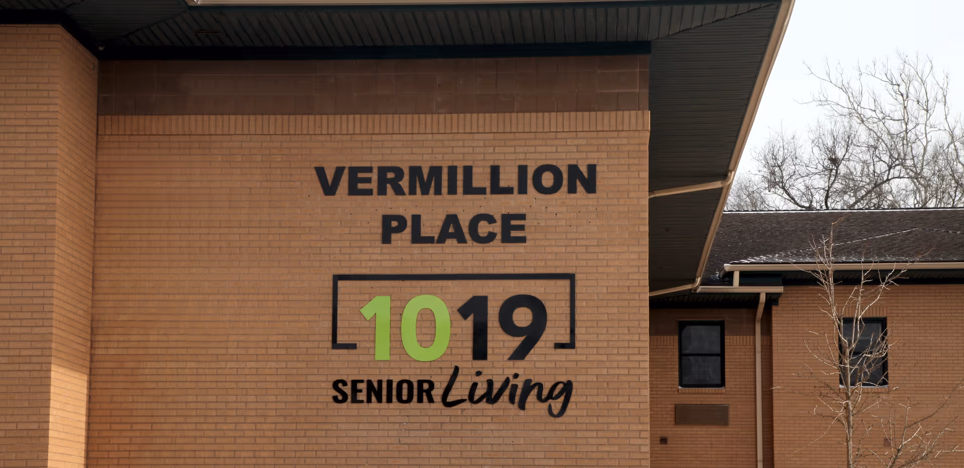 Brick exterior wall of a senior living facility with large signage reading "Vermillion Place" and "1019 Senior Living".