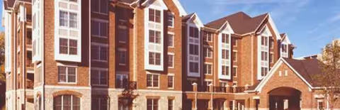 Creekside at the Village exterior: brick senior living building with arched front entrance.