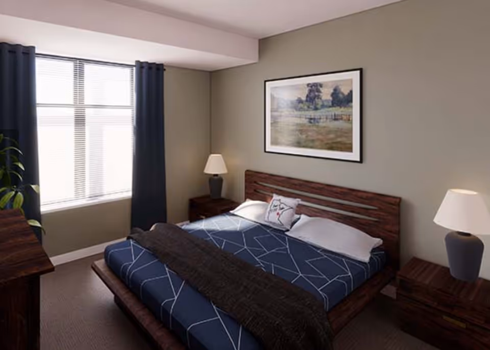 A bedroom with a large bed featuring a blue geometric patterned bedspread and a dark throw blanket. There are two pillows, one with a decorative design. The room has two wooden nightstands each with a lamp, a large window with dark curtains, a wooden dresser, a potted plant, and a framed landscape painting on the wall.