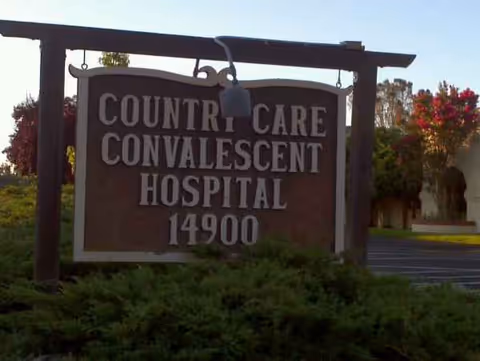 Wooden sign reading 'Country Care Convalescent Hospital' with landscaping in front.