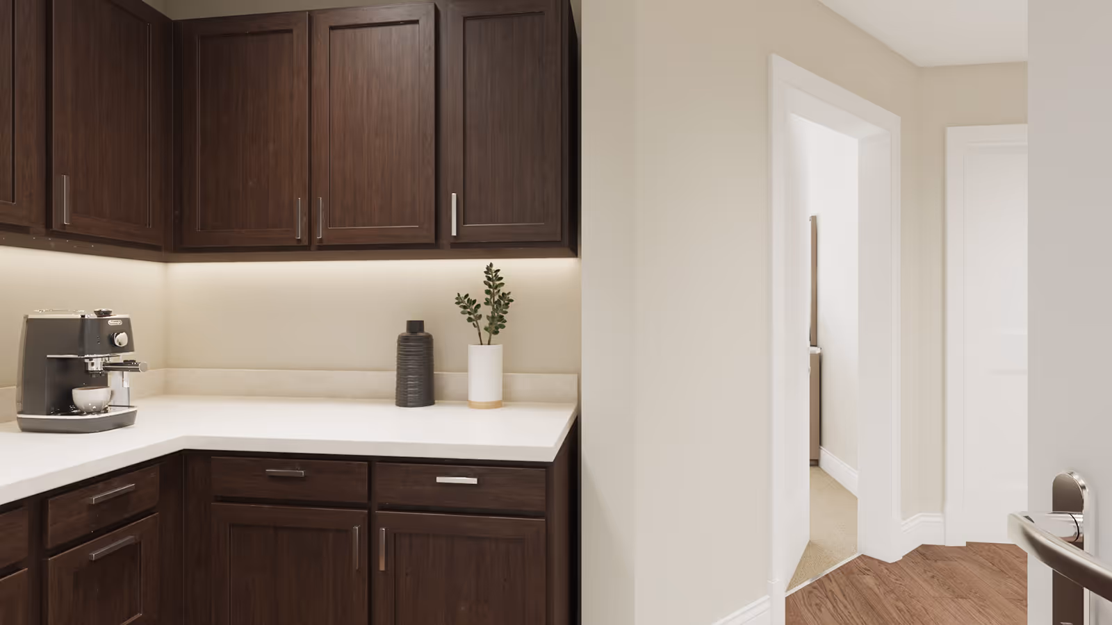 Corner kitchen countertop with dark wood cabinets, a coffee machine, and decorative vases next to a doorway into a hallway.