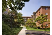 Brick multi-story residential buildings overlooking a landscaped courtyard with a central walkway and trees.