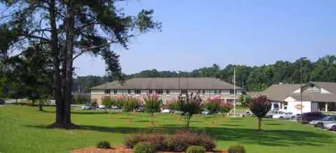Exterior view of Brookdale Meridian with manicured lawn, trees, and parked cars.