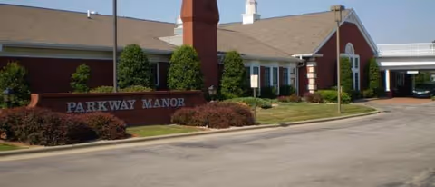Exterior view of a brick senior living facility with a Parkway Manor sign and landscaping.