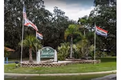 Entrance sign for Pleasant Living Mobile Home Park surrounded by flags and greenery.