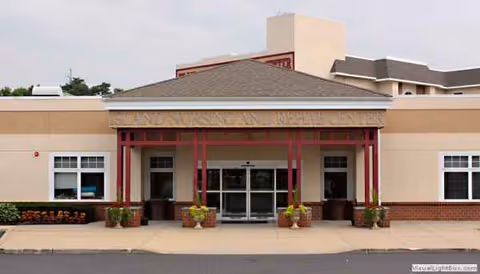 Front entrance of Island Nursing & Rehab Center with red columns and potted plants.