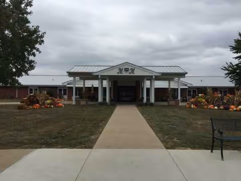 Monroe Manor entrance with a walkway, pumpkins, and a brick front facade.