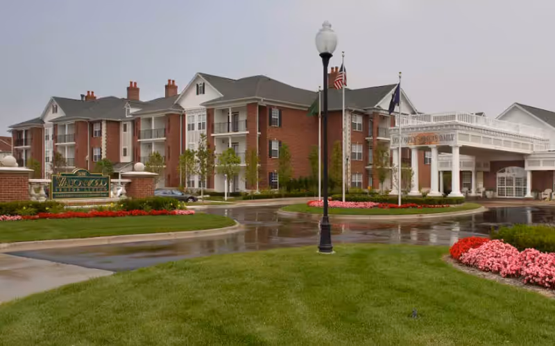 Front view of the Waltonwood Lakeside senior living building with a circular drive, portico entrance, and landscaped lawns and flowerbeds.