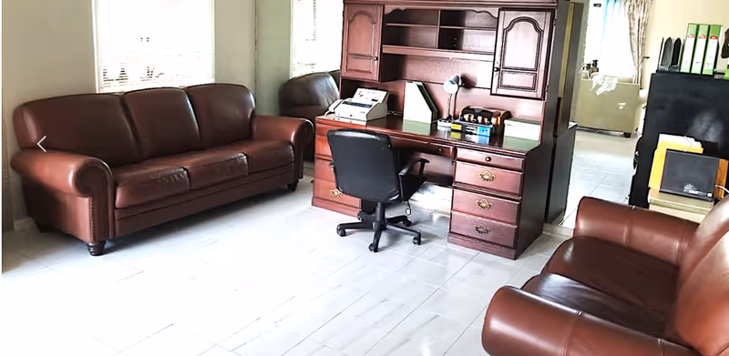 Leather couches and a wooden desk with hutch in a bright common interior area