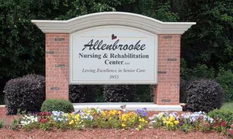 Brick entrance sign for Allenbrooke Nursing & Rehab Center with colorful flowers.