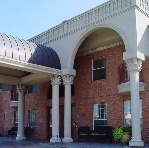 Brick senior living facility exterior with columns, arches and a covered entrance.