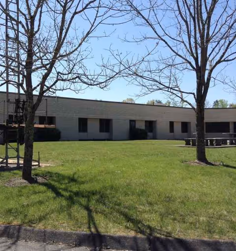 Single-story brick facility with a grassy lawn and leafless trees outside.