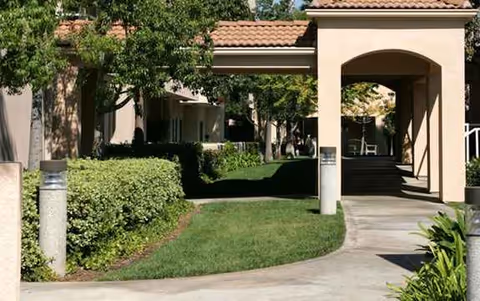 Exterior view of Morningside of Fullerton entrance with a covered archway and landscaped path